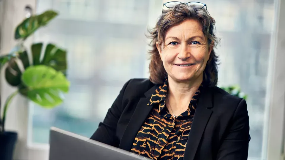 Kvinna vid skärm. grön växt. Foto