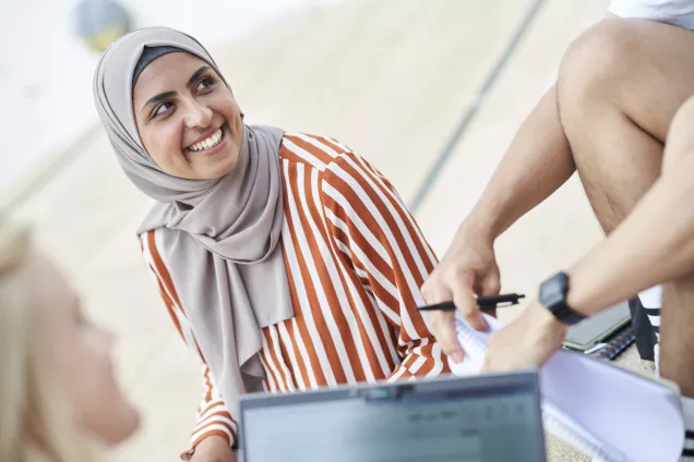Kvinnlig student sittandes utomhus i Helsingborg tillsammans med andra stdudenter. Foto
